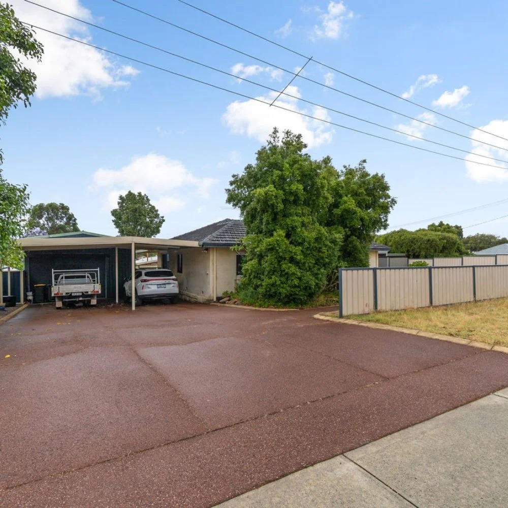 A single-storey home with a carport and wide paved driveway